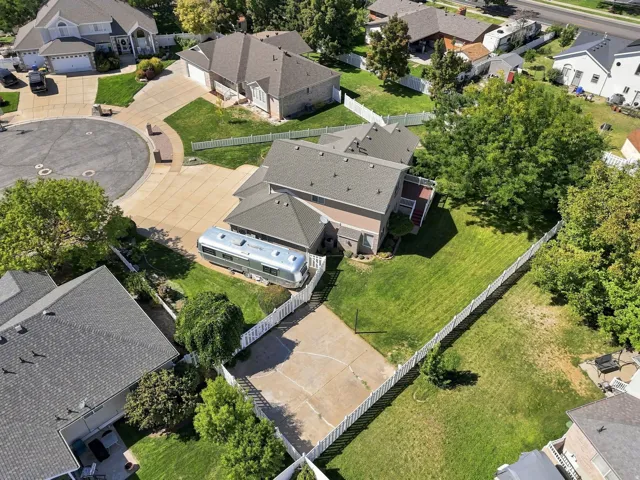 Expansive property with a large backyard featuring a paved court, mature trees, and a white picket fence
