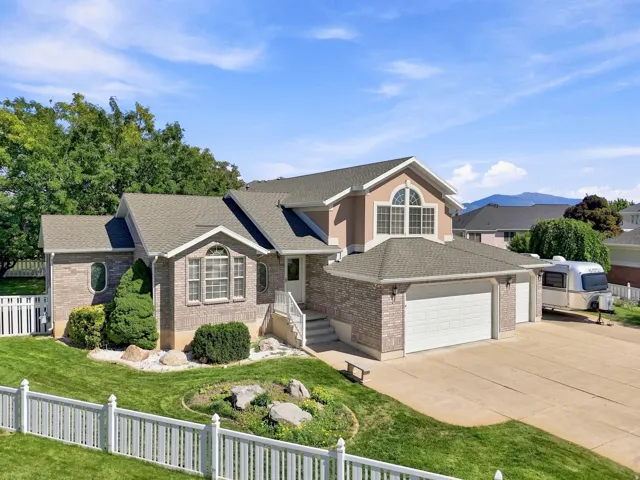 Two-story residence featuring brick and stucco exterior, arched windows, an attached two-car garage, and a concrete driveway