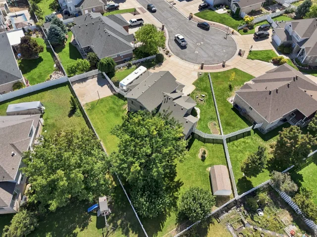 Expansive lot featuring mature trees, a manicured lawn, and a storage shed