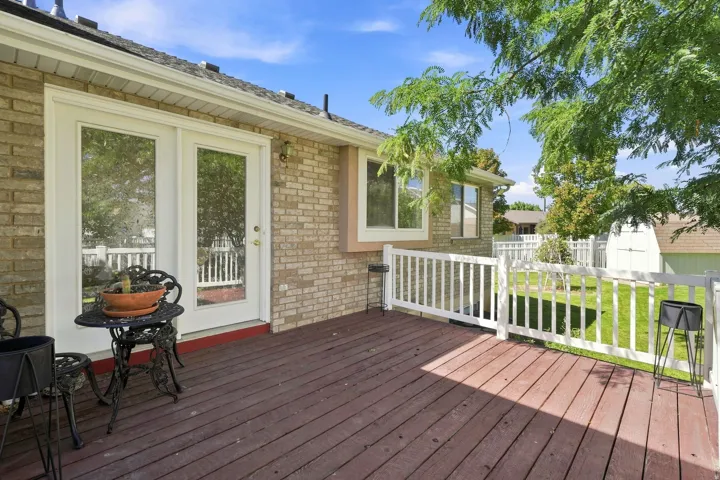 Expansive wood deck with white railing, brick exterior, and dual glass panel doors