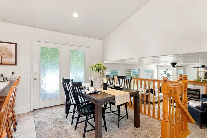 Recessed lighting, vaulted ceiling, white French doors with privacy glass, wood railing, and tiled flooring