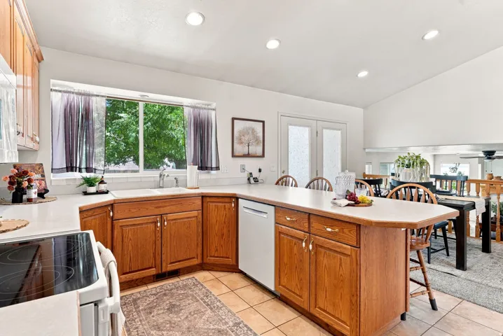 Kitchen featuring wood cabinetry, solid surface countertops, a white subway tile backsplash, and a built-in dishwasher