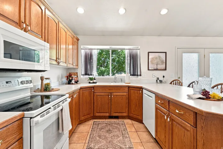 U-shaped kitchen featuring wood cabinetry, white countertops, built-in microwave, and tile flooring