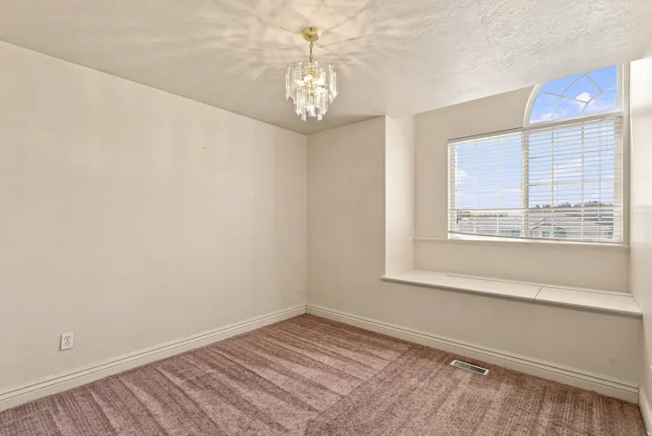 Arched window, built-in window seat, patterned carpet, and a decorative ceiling light fixture
