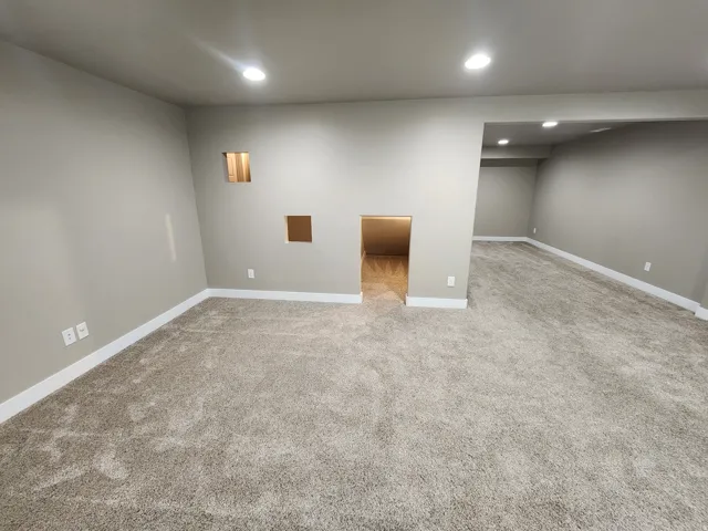 Recessed ceiling lighting, light gray wall paint, gray carpet flooring, white trim, interior wall cut-outs