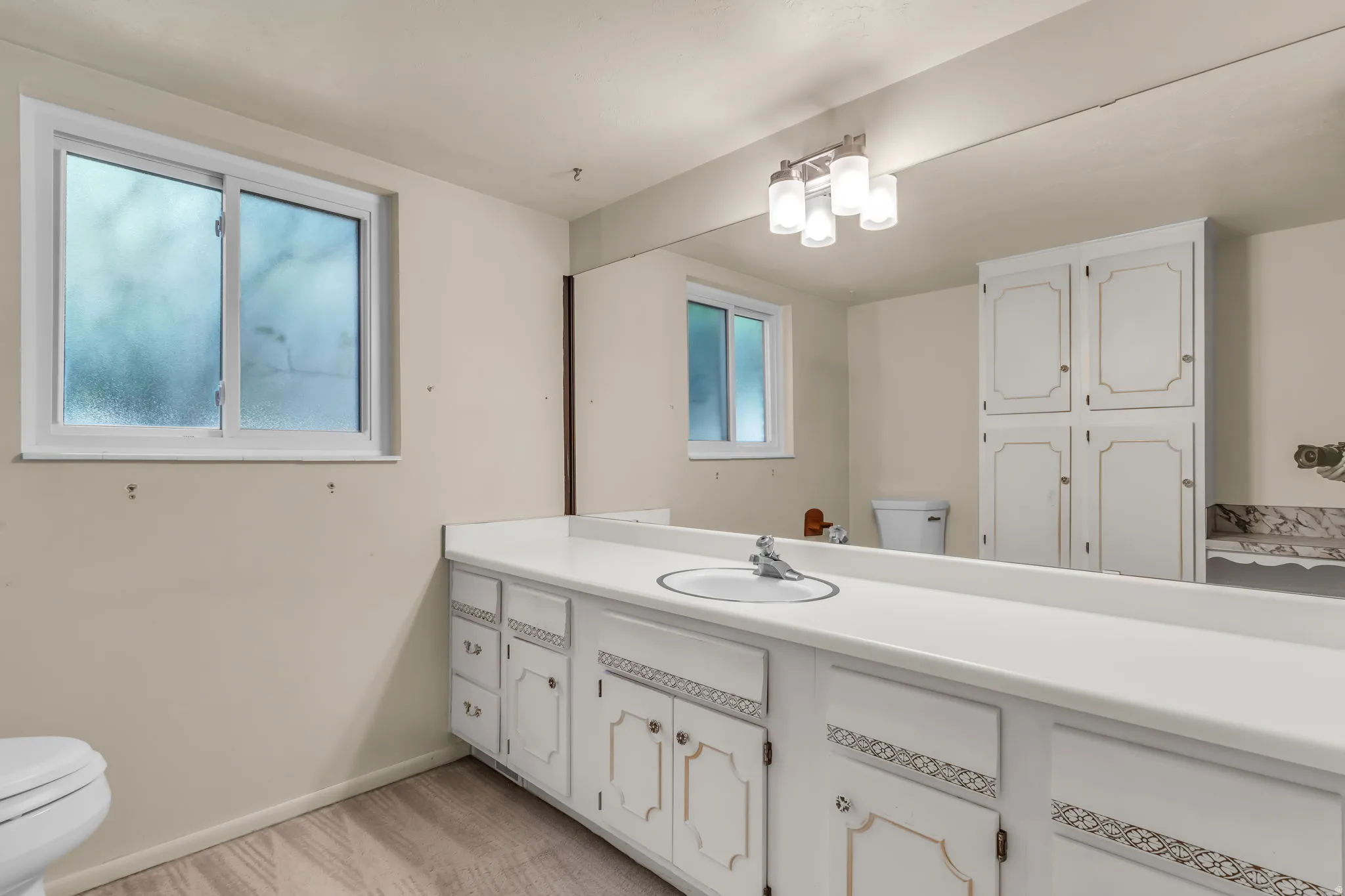 Extended vanity with an integrated sink, white cabinetry, and wood-finish flooring