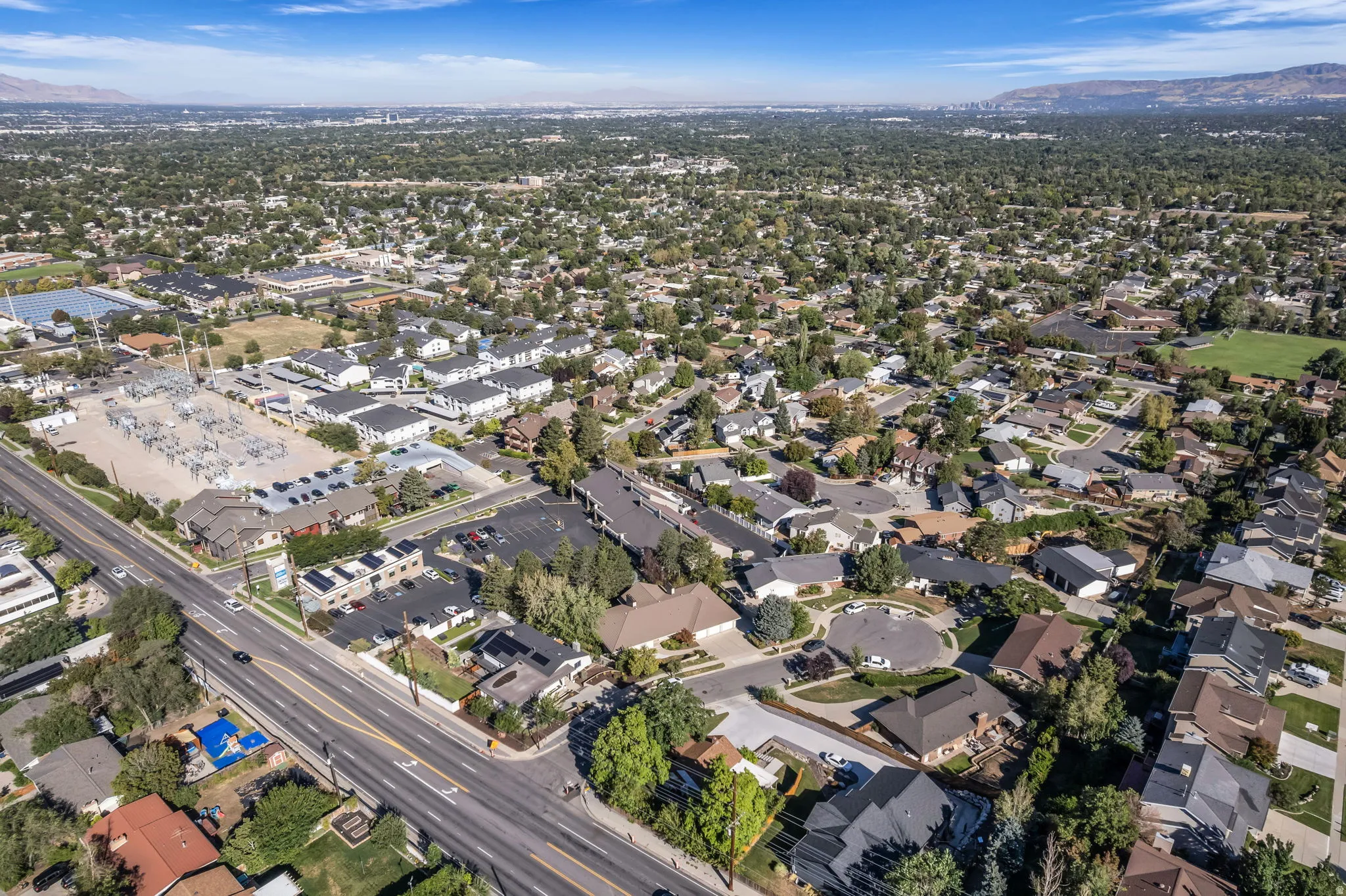 Expansive aerial capturing residential neighborhoods with varied housing styles and mature tree coverage