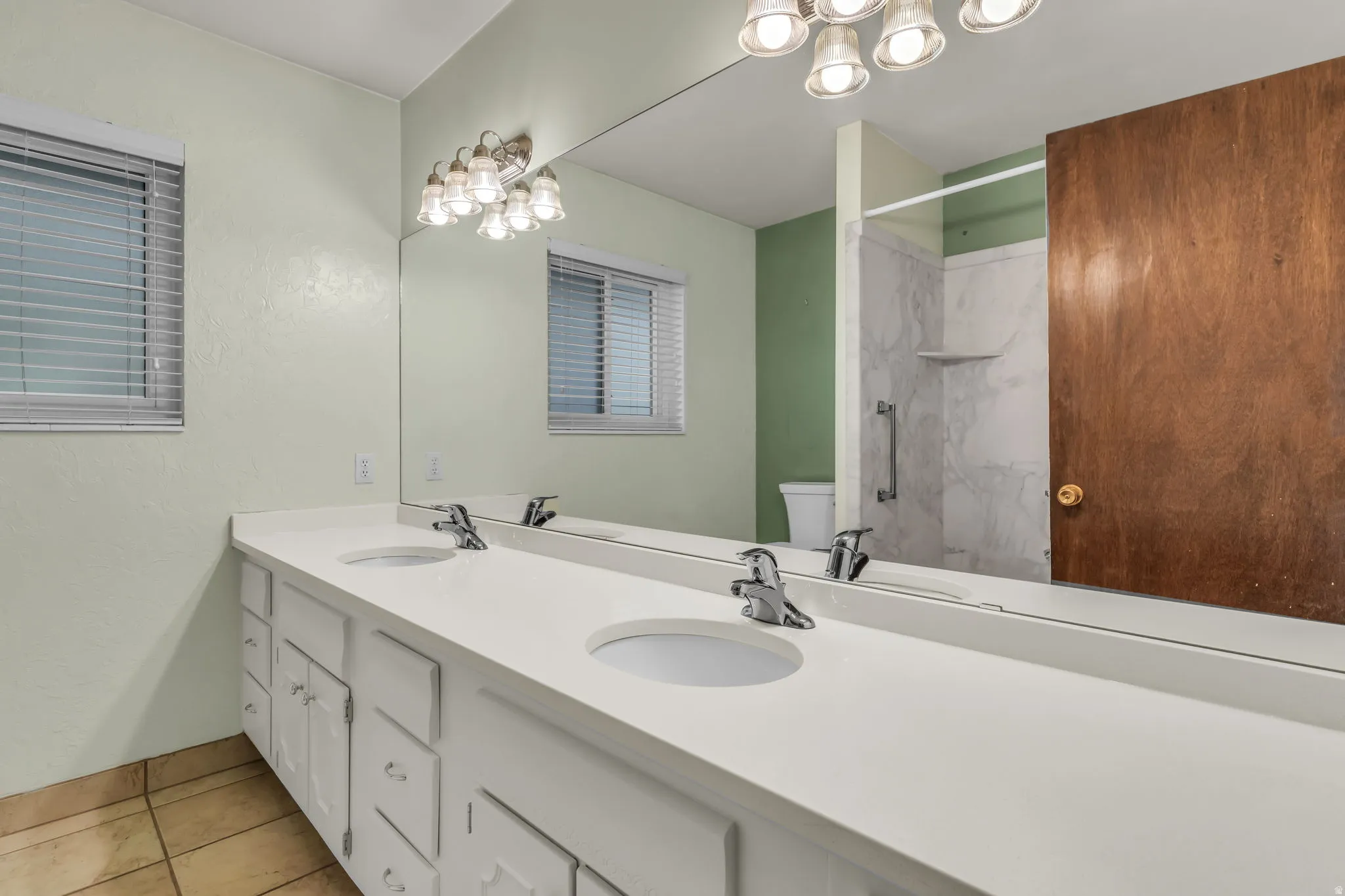 Dual vanity with white cabinetry, integrated sinks, chrome fixtures, and a full-width mirror
