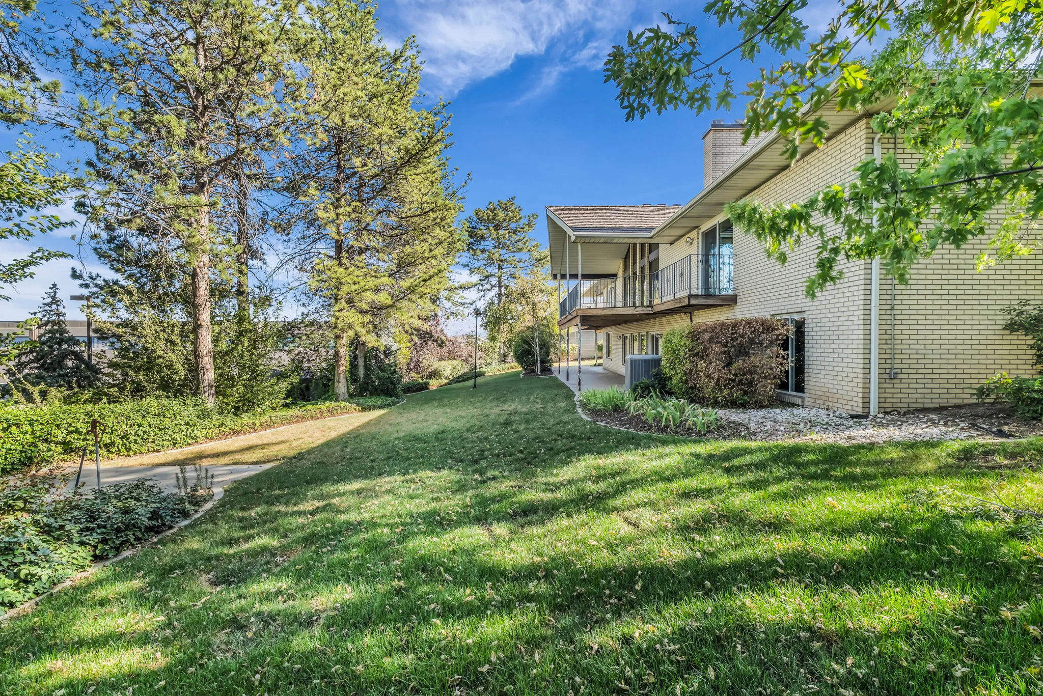 Expansive lawn with mature trees and a paved pathway