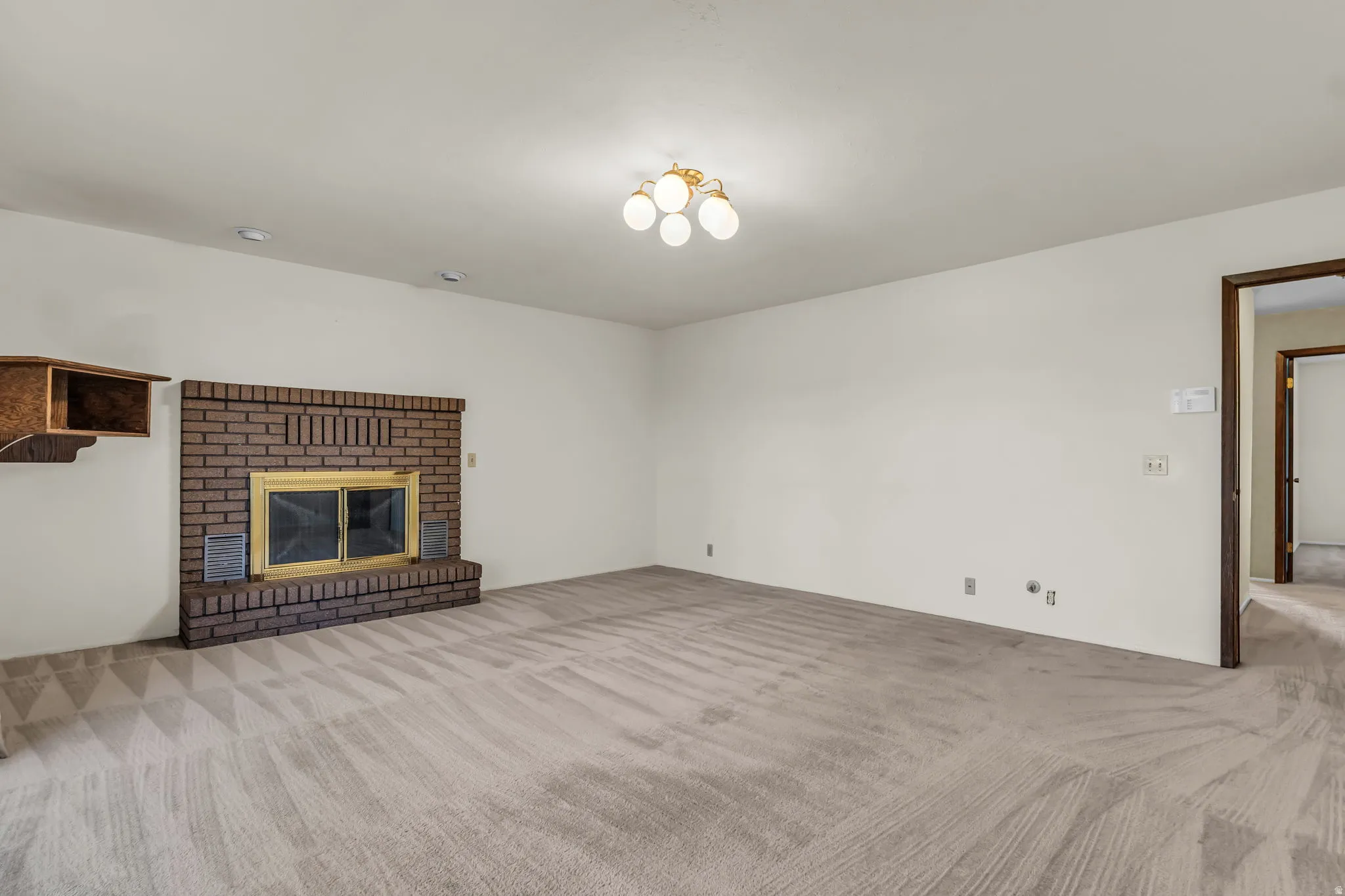 Recessed lighting and a gold-finished ceiling fixture illuminate this carpeted room