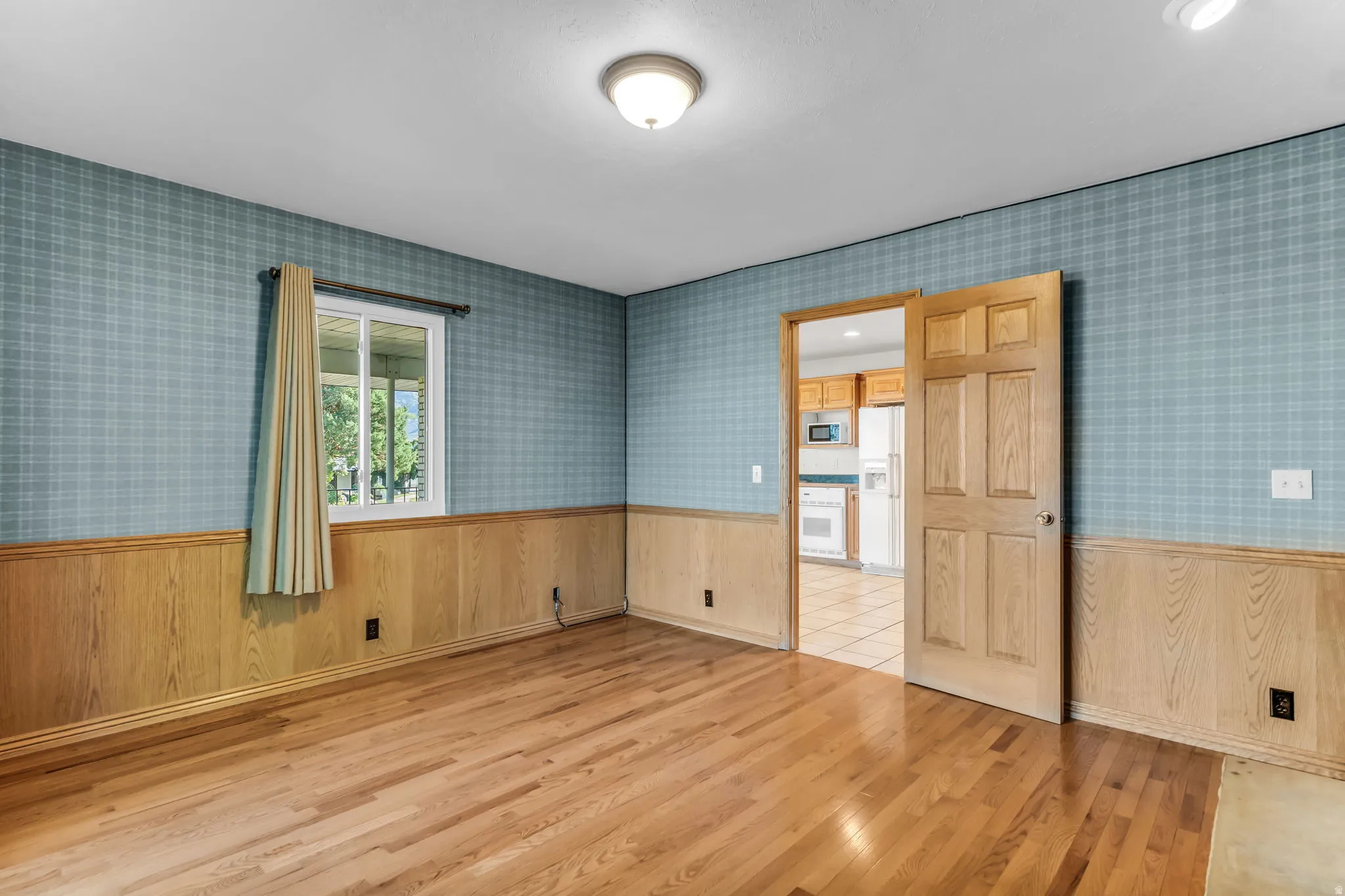 Hardwood flooring, wood paneling, plaid wallpaper, recessed ceiling light, paneled wood door