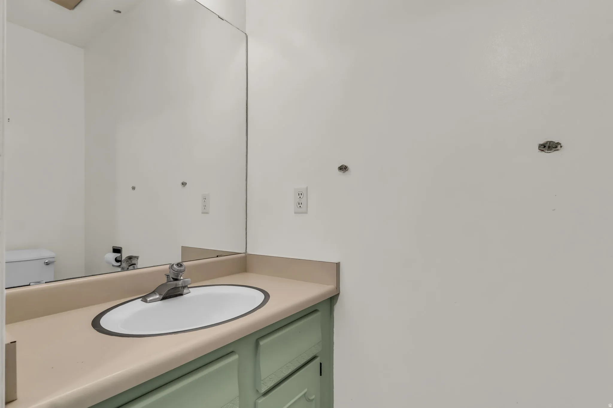 Vanity with an integrated sink, light-toned countertop, and a large wall-mounted mirror