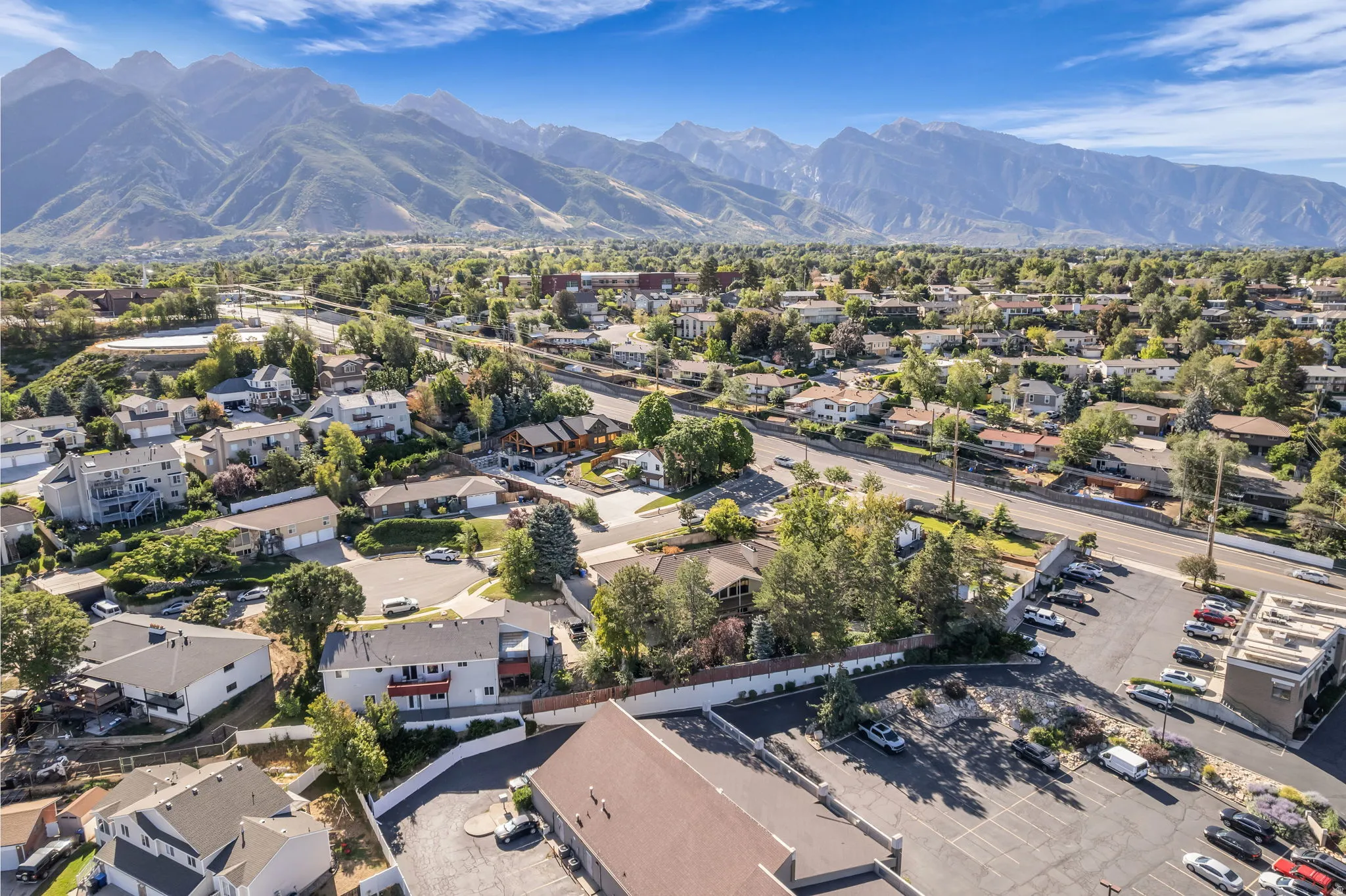 Expansive mountain backdrop, established neighborhood setting, mature trees, and a commercial parking area