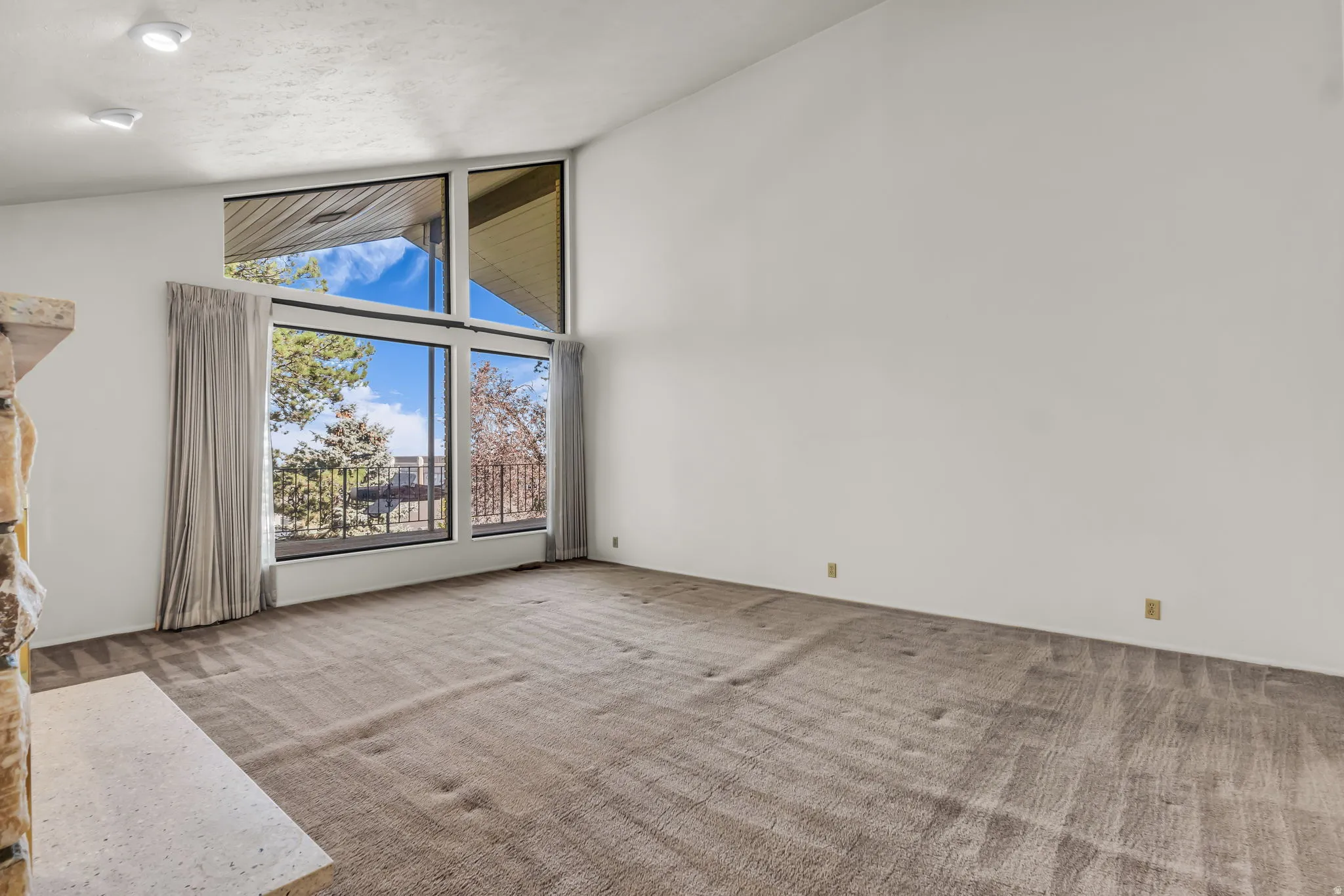 Vaulted ceiling with recessed lighting, large picture windows, and a stone-clad fireplace