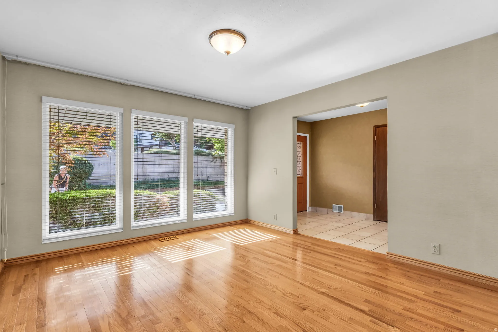 Hardwood flooring, three large windows, neutral wall tones, recessed entryway, and flush mount lighting
