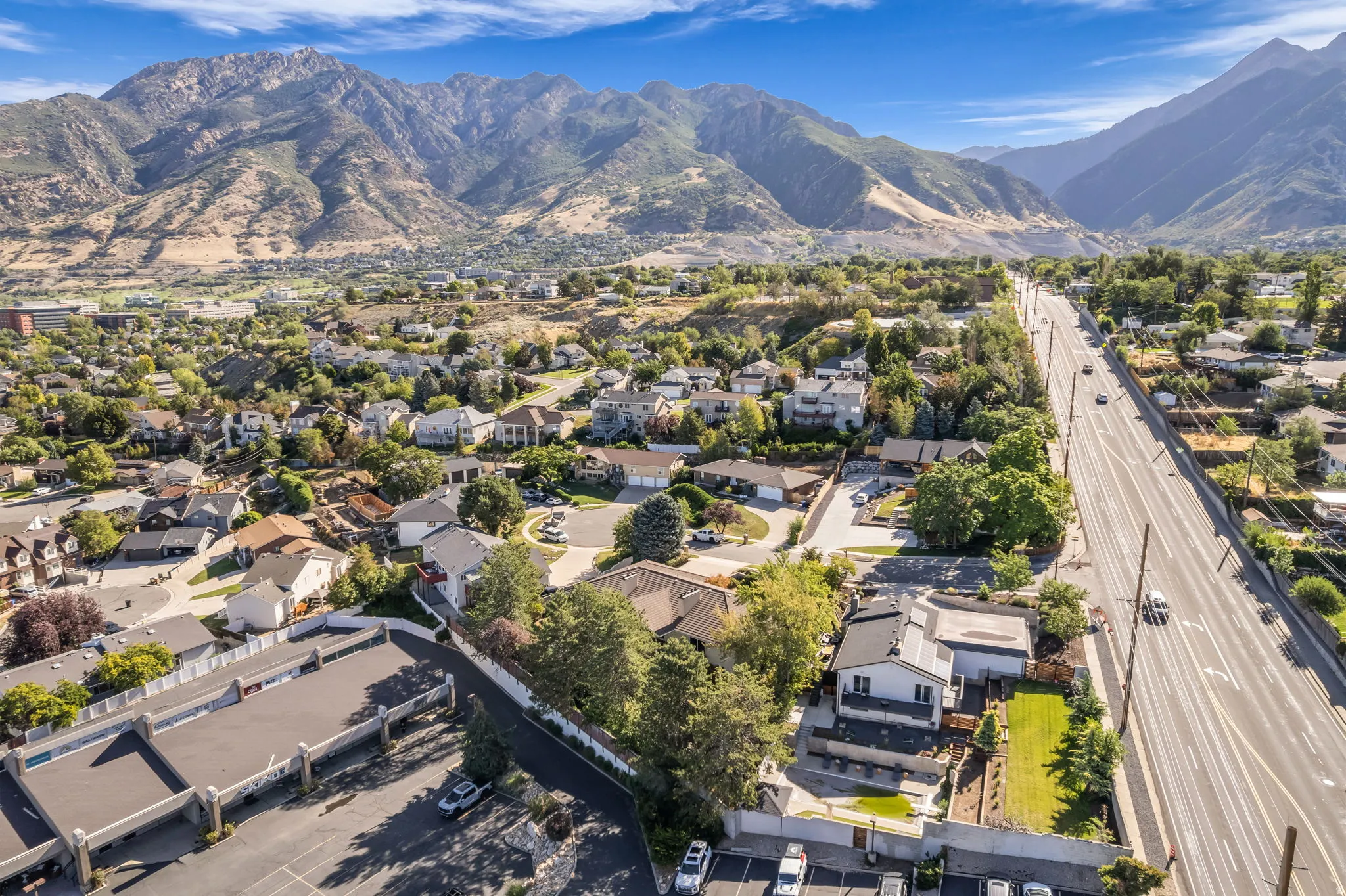 Residential property with surrounding mountainous terrain, adjacent to a multi-lane road