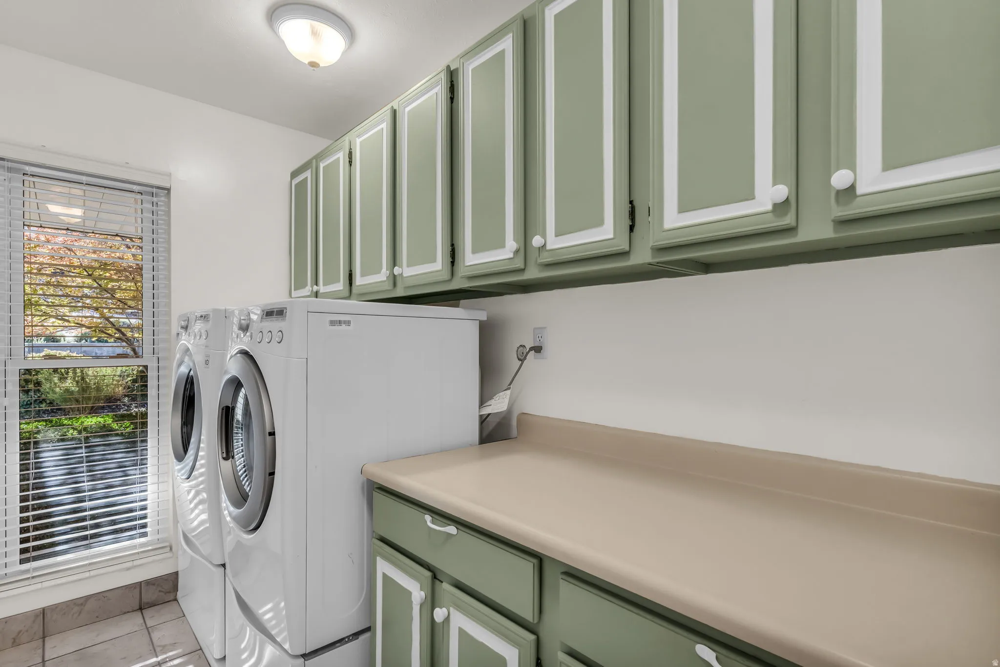Upper and lower cabinetry with decorative molding, a light-toned countertop, and tiled flooring