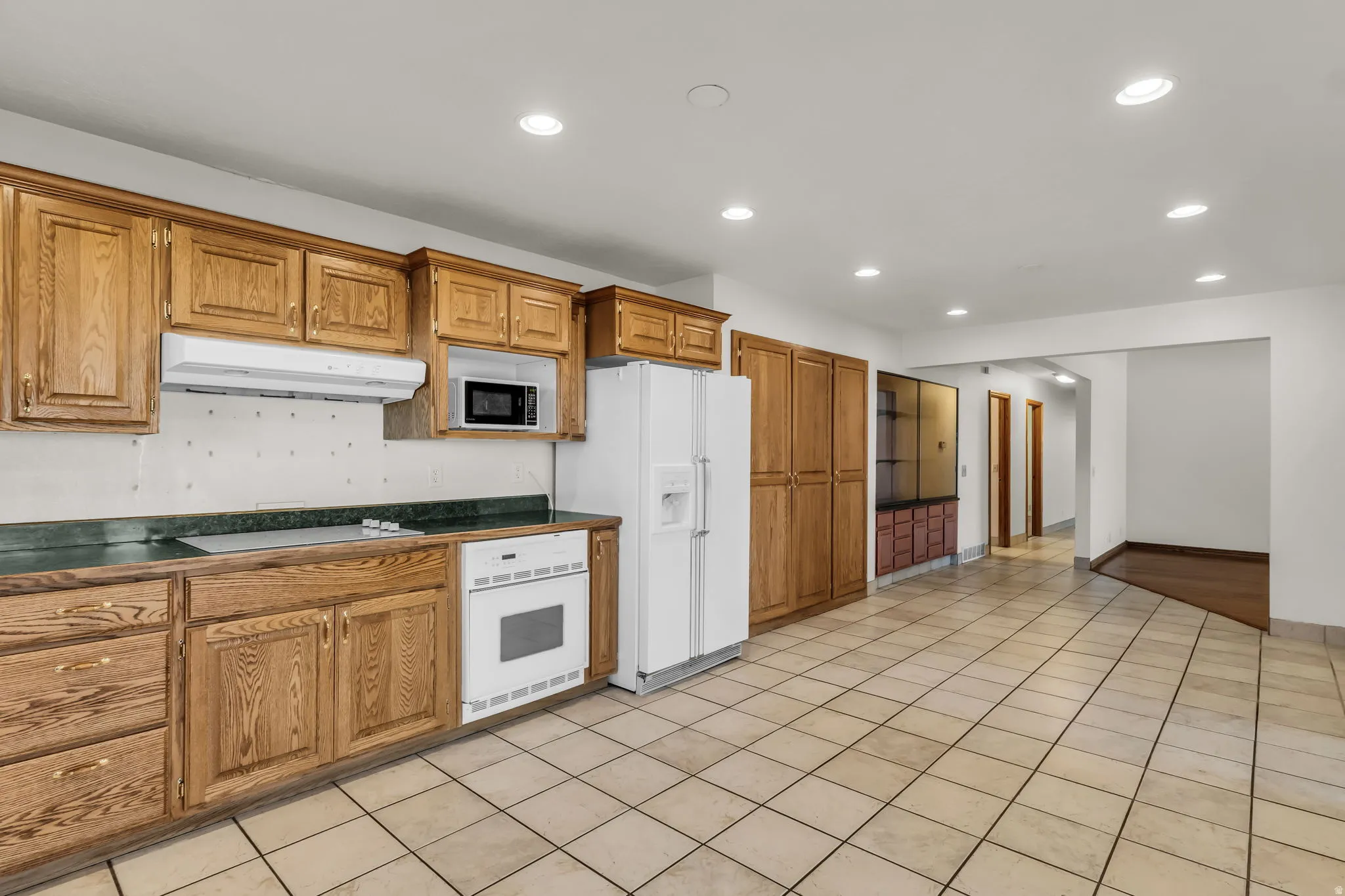 Kitchen featuring wood cabinetry, integrated microwave, built-in oven, and tile flooring