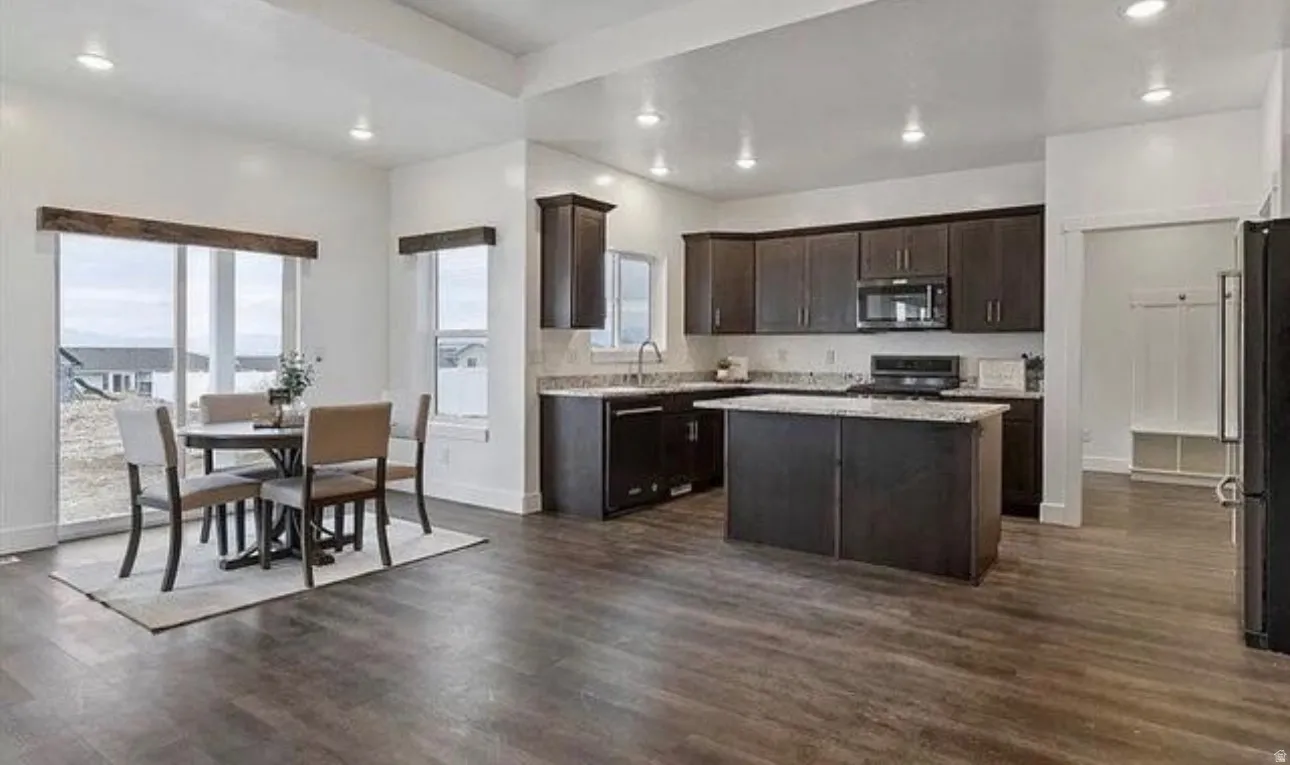 Open-concept living space with dark wood-finish flooring, recessed lighting, white walls, dark wood-finish cabinetry, and a kitchen island with stone countertops