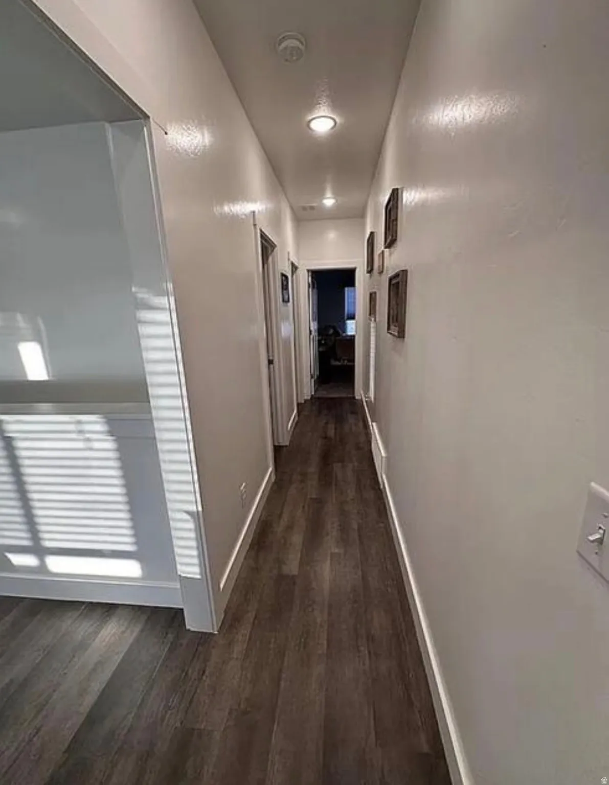 Recessed lighting illuminates the hallway with wood-finish flooring