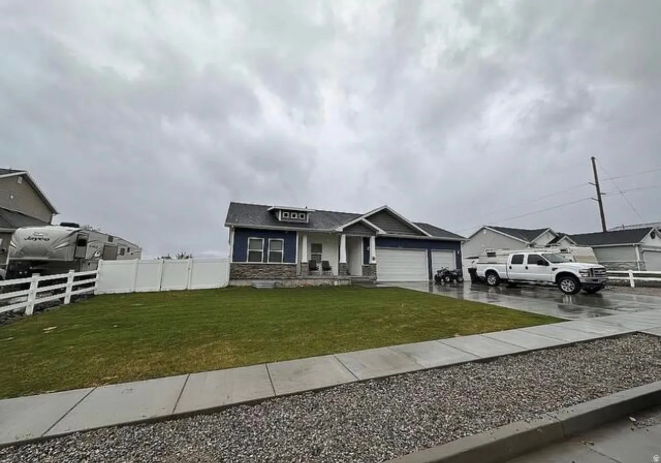 Single-story residence featuring a two-car garage, stone accent siding, and a covered porch