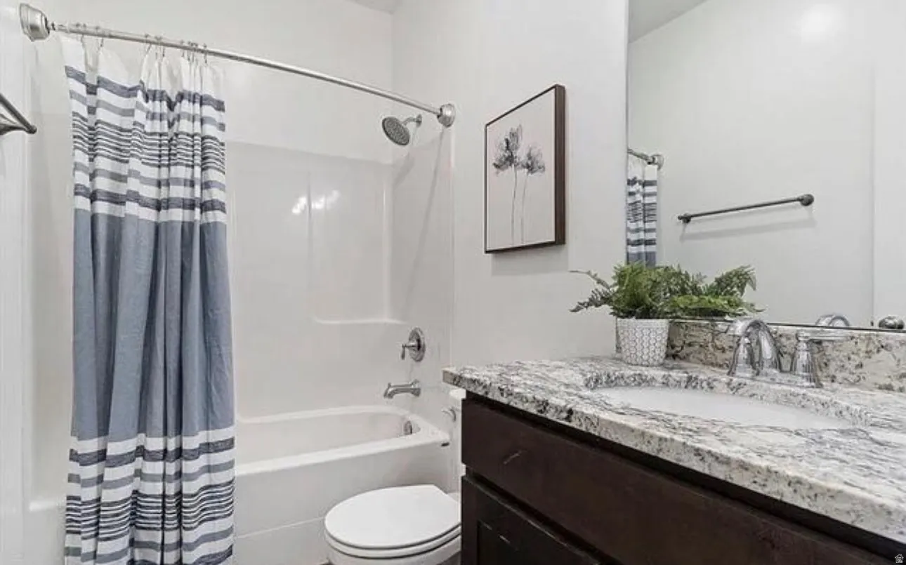 Bathroom featuring a white bathtub and shower surround, a dark wood-finish vanity with a light-toned countertop, and an integrated rectangular sink