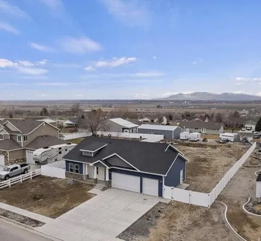 Modern single-story residence featuring a two-car garage, concrete driveway, and full white vinyl fencing