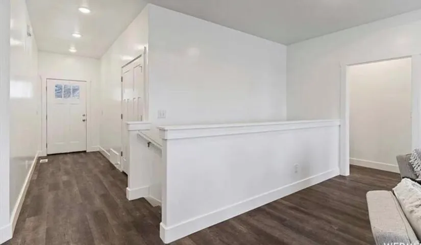 Laminate wood-finish flooring, recessed lighting, and white trim accents