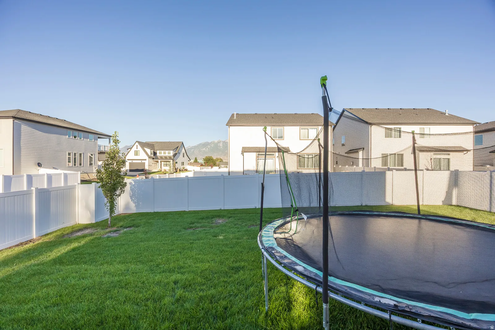 Expansive lawn area with a white privacy fence