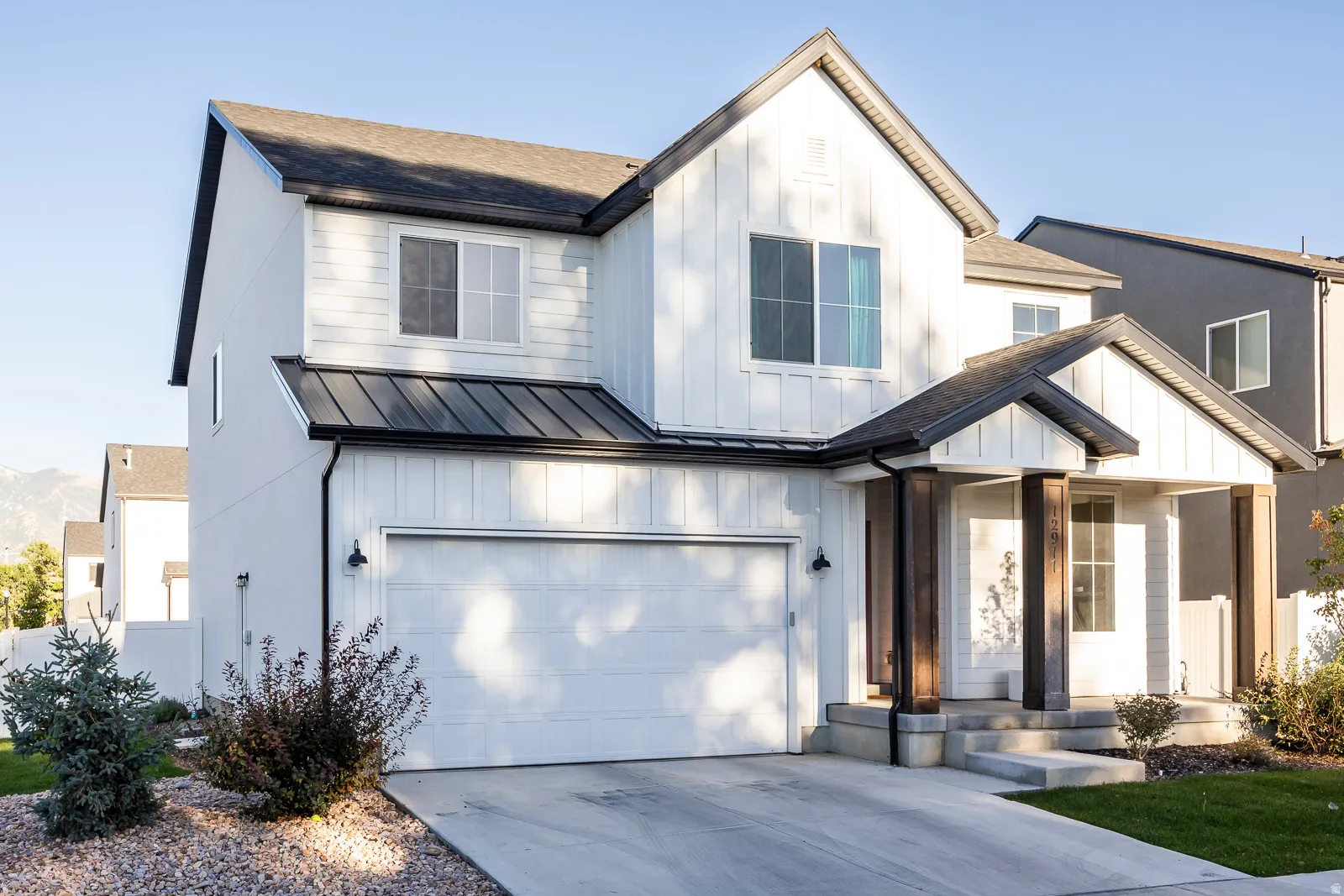 Modern farmhouse-style exterior featuring white vertical siding and dark trim