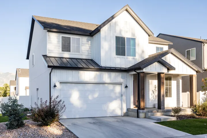 Modern farmhouse-style exterior featuring white vertical siding and dark trim