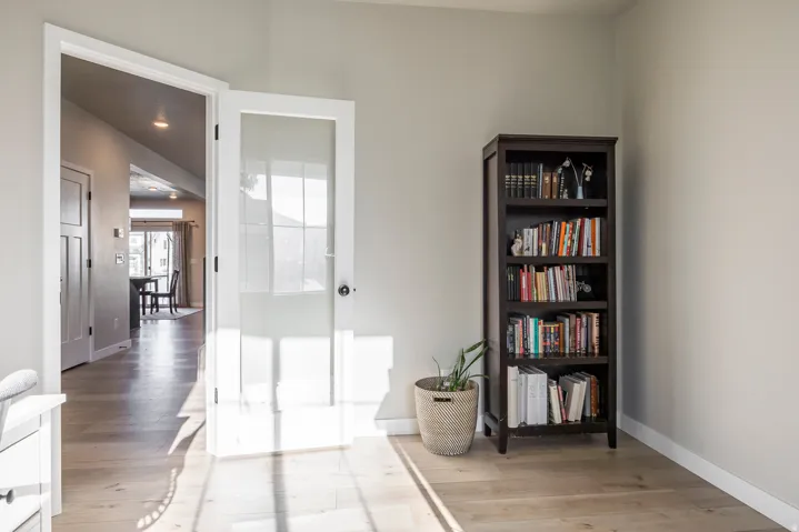 Light wood-finish flooring, white trim throughout, and a frosted glass-paneled door
