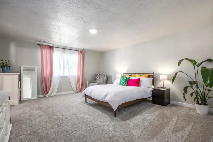 Window with sheer and colored drapes, light gray carpet, and light gray walls
