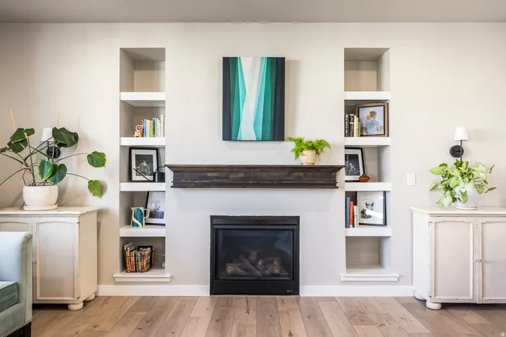Fireplace featuring a dark wood mantel and a black surround, flanked by built-in recessed shelving