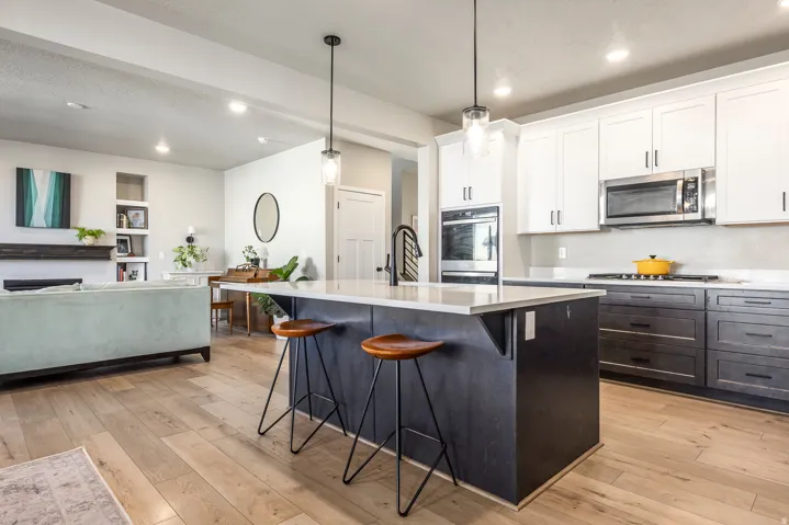Gourmet kitchen featuring a central island, stainless steel appliances, two-tone cabinetry, and wood-finish flooring