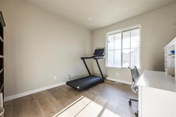 Light wood-finish flooring, neutral wall paint, and a large window with white trim