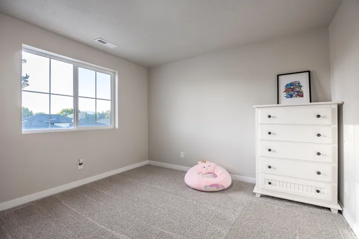 Neutral paint palette, expansive window with white grid, and plush gray carpeting