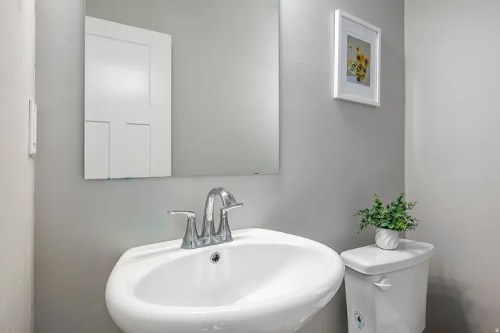 Pedestal sink with chrome fixtures and a wall-mounted mirror