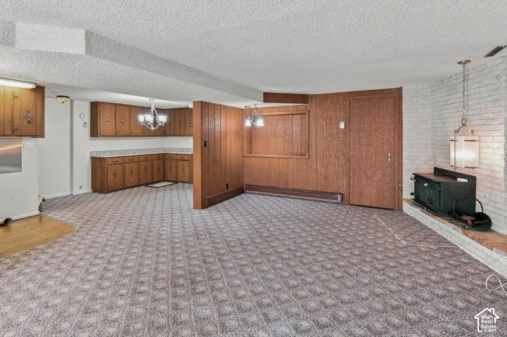 Spacious room featuring patterned carpet, wood-finish paneling, and a white brick fireplace with a hearth