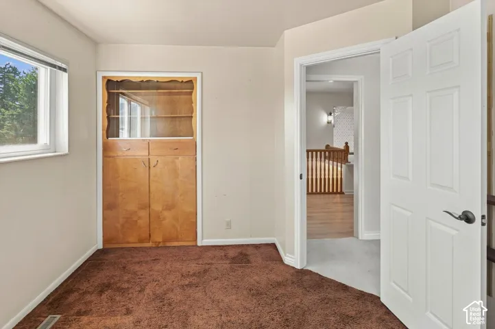 Built-in wood-finish cabinetry featuring glass display shelves, and a window with white trim