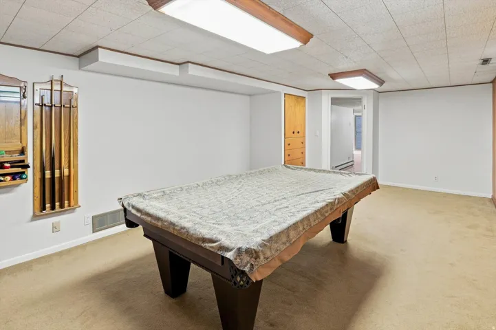Recessed ceiling with acoustic tiles, plush carpet flooring, wall-mounted storage cabinet, wood-finish trim, and built-in lighting fixtures