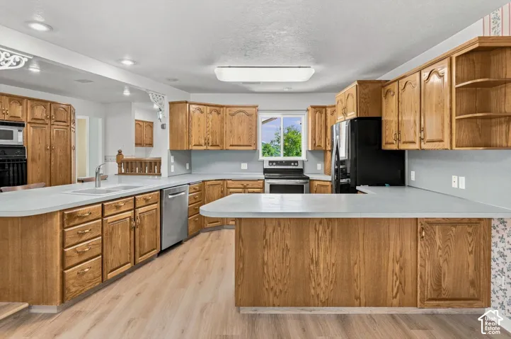 Expansive kitchen with wood cabinetry, light countertops, wood-finish flooring, and a stainless steel dishwasher