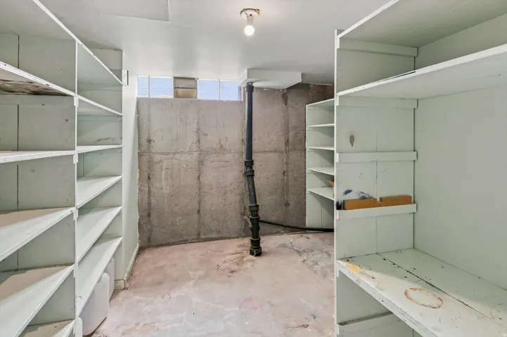 Built-in shelving units, concrete foundation walls, ceiling-mounted light fixture, and glass block windows