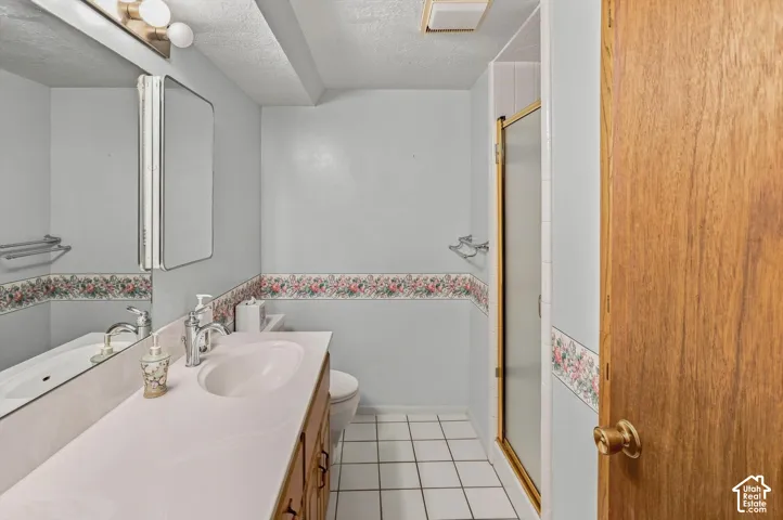Vanity with integrated sink, wood-finish cabinetry, wall-mounted mirror, and tile flooring