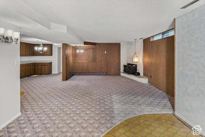 Lower-level space with patterned carpeting, built-in wood cabinetry, and a brick fireplace