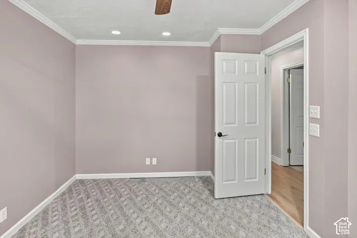 Recessed ceiling lights, crown molding, wood-finish ceiling fan, paneled interior door, and patterned carpet