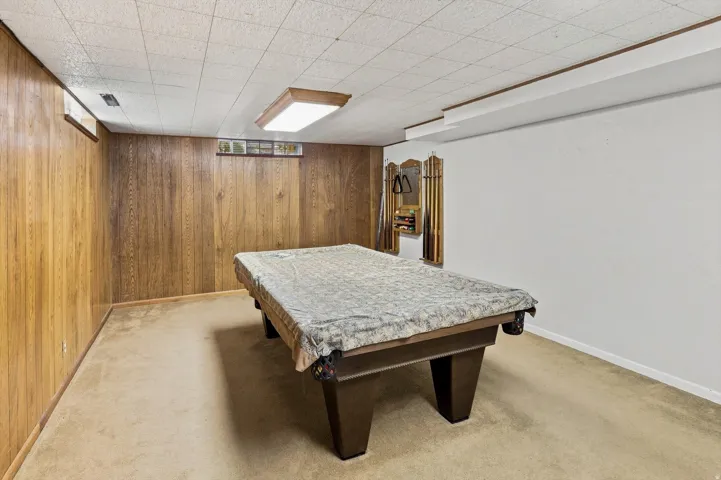 Wood-paneled wall, textured ceiling, carpeted flooring, and recessed lighting