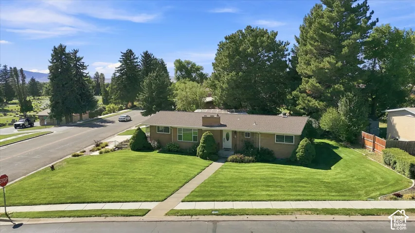 Single-story residence featuring a traditional brick exterior, gabled roof, and a mature landscaped yard with a concrete pathway
