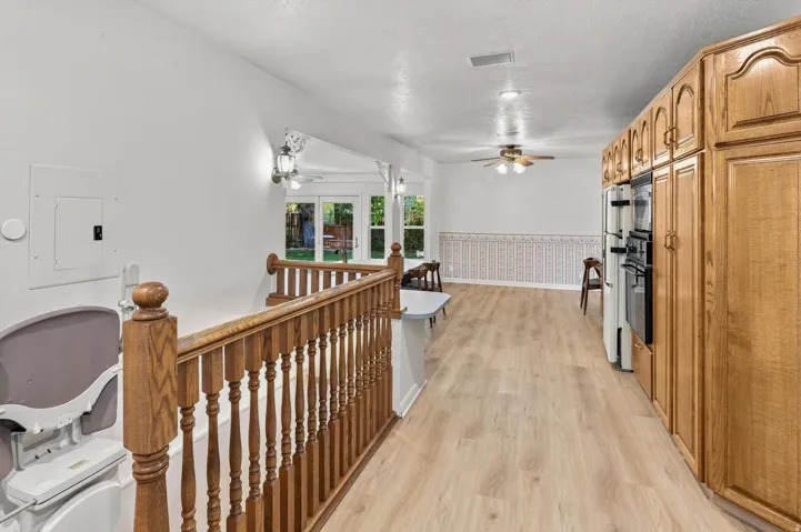 Wood-finish flooring throughout, full-height built-in cabinetry, and a ceiling fan with integrated lighting