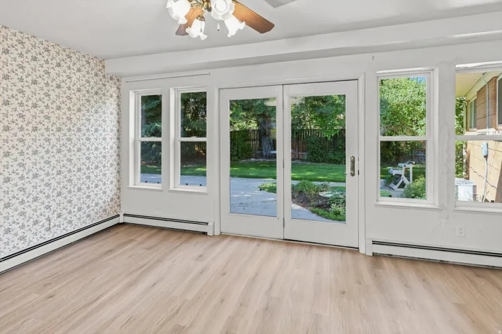Wood-finish flooring, white trim, and a ceiling fan with light fixture